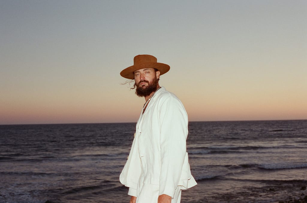 RY X on the beach with the sunset in the background