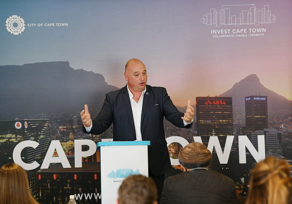 Alderman James Vos speaking passionately while in front of an Invest Cape Town media wall.