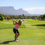 Lady golfer on putting green with view of Table Mountain