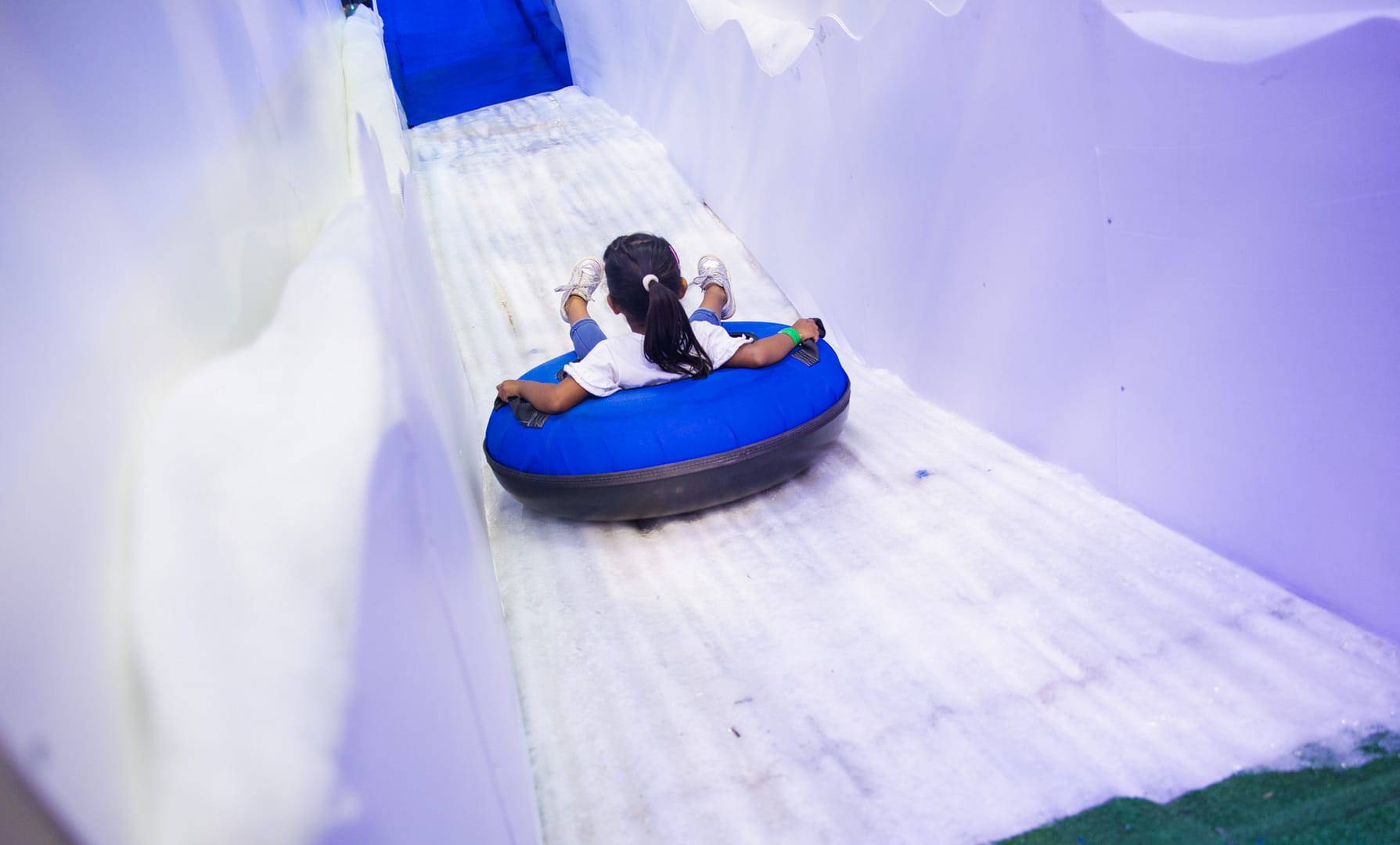 Girl sliding down ice slides on a blue inflatable tube